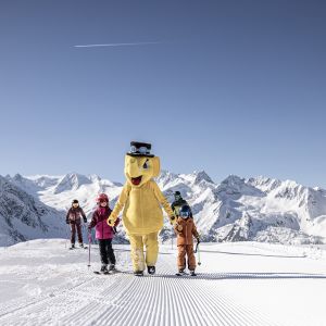 Kinder mit Maskottchen auf der Piste im Familienskigebiet